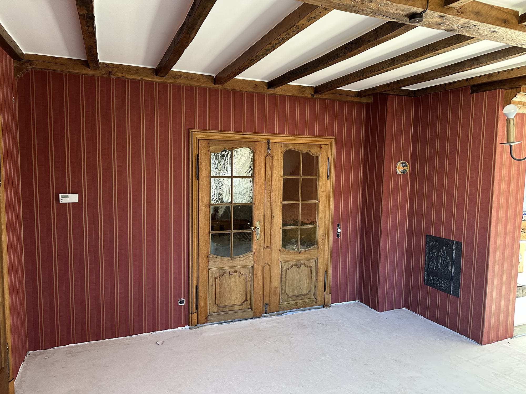 Tapezierter Wohnraum mit roter Streifentapete und historischen Holzbalken